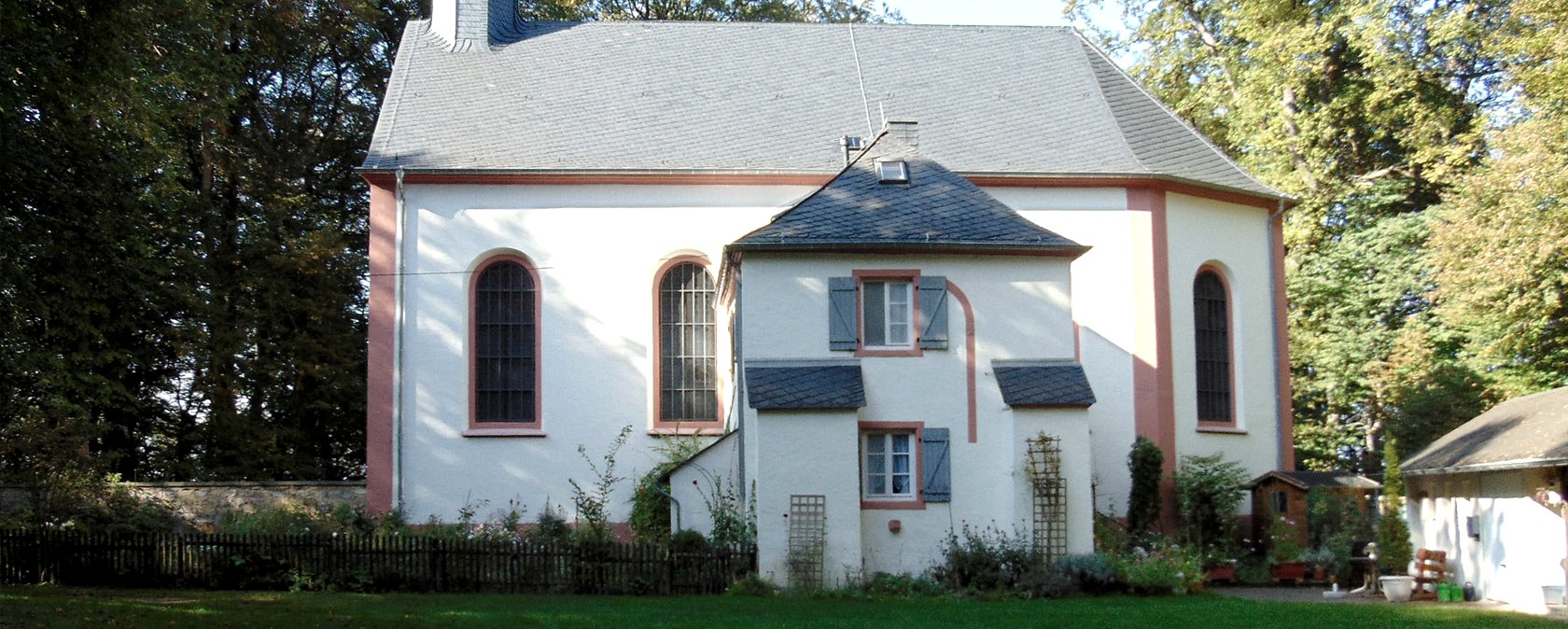 Schankweiler Klause, ein historisches Gebäude mit weißen Wänden und roten Akzenten, umgeben von Bäumen., © Chr. Teuschler Schankweiler Klause, ein historisches Gebäude mit weißen Wänden und roten Akzenten, umgeben von Bäumen., © Chr. Teuschler