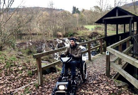 Dr. Holger Tülp testet ein Gespann aus Rollstuhl und Zuggerät auf dem zertifizierten barrierefreien Komfort-Weg rund um den Stausee Irrhausen. , © Naturpark Südeifel/Dr. Holger Tülp Dr. Holger Tülp testet ein Gespann aus Rollstuhl und Zuggerät auf dem zertifizierten barrierefreien Komfort-Weg rund um den Stausee Irrhausen. , © Naturpark Südeifel/Dr. Holger Tülp