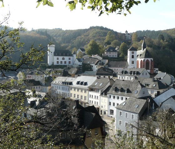 Panoramablick auf Neuerburg mit historischen Gebäuden, einer Kirche und bewaldeten Hügeln im Hintergrund., © Christian Calonec-Rauchfuss, Felsenland Südeifel Tourismus GmbH Panoramablick auf Neuerburg mit historischen Gebäuden, einer Kirche und bewaldeten Hügeln im Hintergrund., © Christian Calonec-Rauchfuss, Felsenland Südeifel Tourismus GmbH