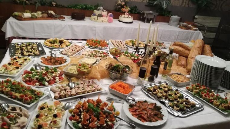 Un buffet riche avec différentes entrées, salades et fruits de mer. Au milieu se trouvent des petits pains frais et une sélection de desserts.