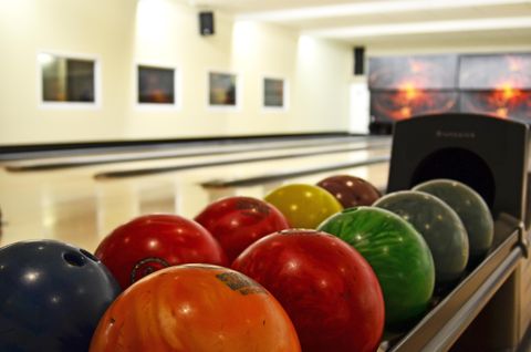 Een bowlingbaan met kleurrijke bowlingballen in een accommodatie. De omgeving is helder en uitnodigend.