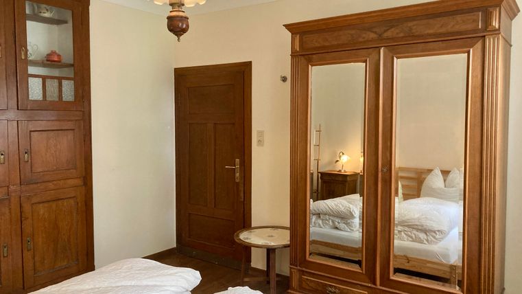 Une chambre confortable avec un grand miroir et une armoire en bois. Il y a deux lits et une table décorative.