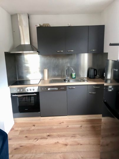 A modern kitchen with dark cabinets and stainless steel surfaces. It is well-equipped with a stove, oven, and sink.
