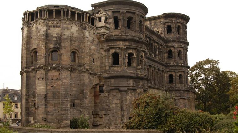 Une vieille ruine romaine avec de nombreuses fenêtres et une architecture intéressante. Entourée de parterres de fleurs et d'arbres.
