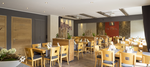 Een modern restaurant met houten tafels en stoelen. De gezellige sfeer wordt versterkt door zachte verlichting en decoratieve elementen.