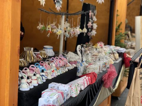 Ein bunter Marktstand mit verschiedenen handgefertigten Dekorationsartikeln. Es gibt viele Süßigkeiten und kleine Geschenke, die zum Kauf angeboten werden.