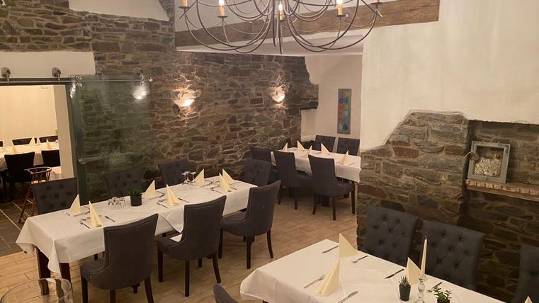 Un restaurant confortable avec des murs en pierre et un éclairage élégant. Les tables sont mises et prêtes pour les invités.