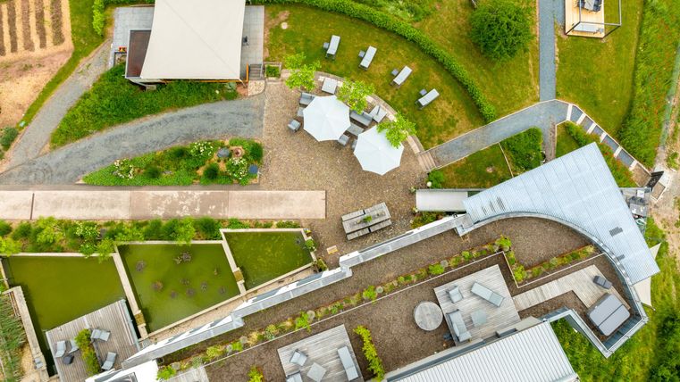 Un paysage de jardin moderne avec des zones de sièges et des chemins. La zone comprend des plantes, des surfaces d'eau et une grande terrasse.