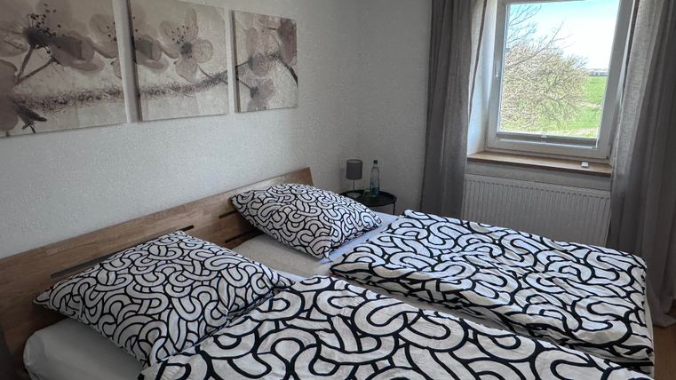 Ein gemütliches Schlafzimmer mit einem Doppelbett und modernem Bettzeug. Ein Fenster bietet einen Blick auf die Landschaft draußen.