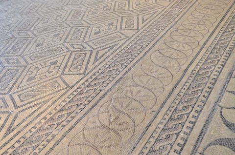 Ein kunstvolles Mosaik mit geometrischen Mustern und wellenförmigen Designs. Die Farbgebung ist dezent und harmonisch.