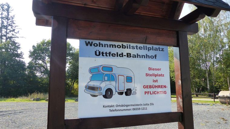 A sign for a motorhome parking area at Üttfeld train station. The parking is subject to fees.