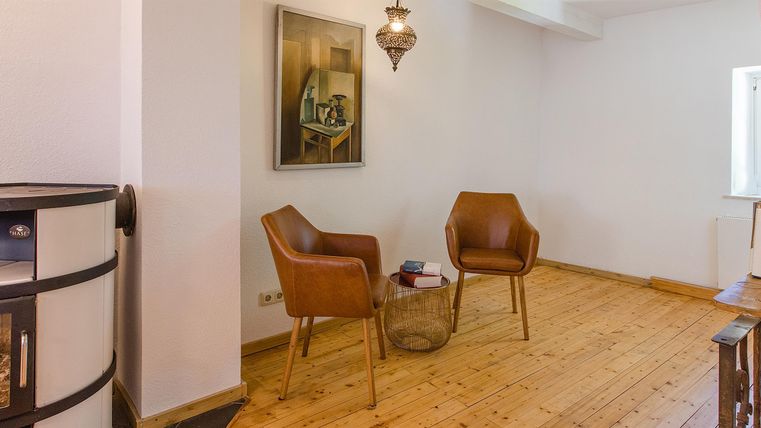 Ein modernes Wohnzimmer mit Holzboden und zwei stilvollen Stühlen. An der Wand hängt ein Kunstwerk, das den Raum gemütlich dekoriert.