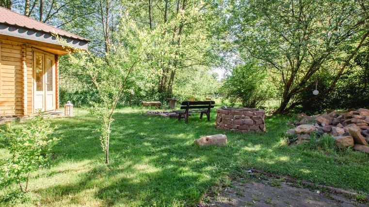 Ein schöner Garten mit einer Holzterrasse und einem Sitzbereich. Umgeben von grünen Bäumen und einer ruhigen Atmosphäre.