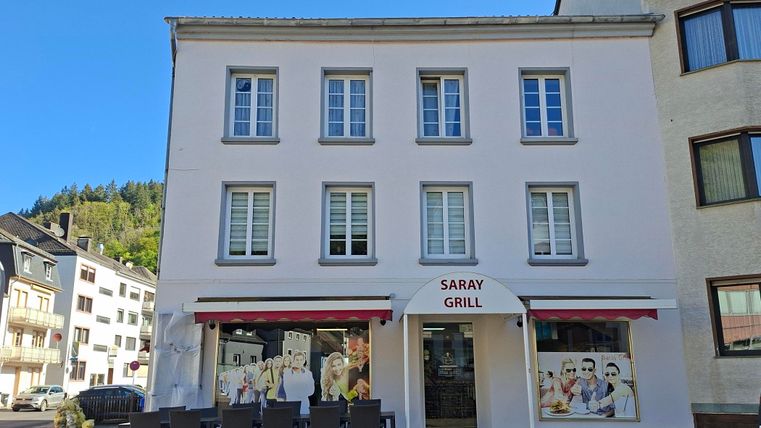 Ein Restaurant namens "Saray Grill" mit einer einladenden Außenfassade. Vor dem Gebäude stehen Tische und Stühle für Gäste im Freien.