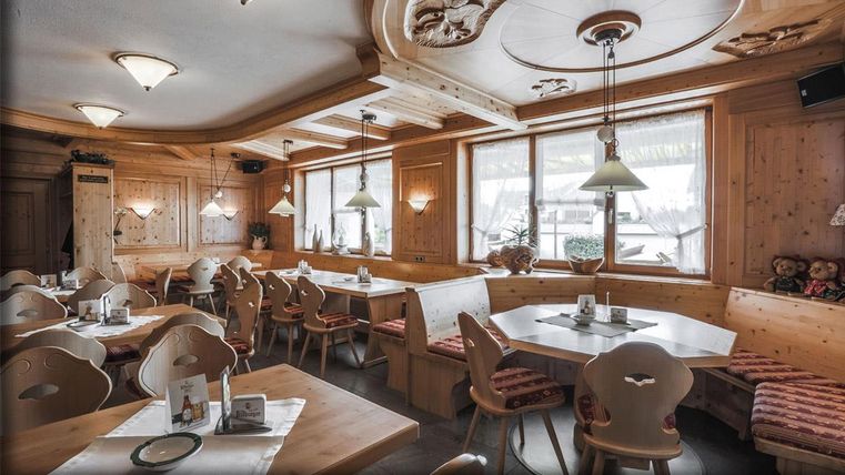 Un restaurant accueillant avec un intérieur en bois et de grandes fenêtres. Les tables sont proprement dressées et l'éclairage est chaleureux et confortable.