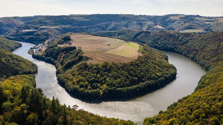 Luftaufnahme einer Flussschleife in einer bewaldeten Landschaft mit Feldern.