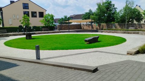 Eine Gruppe von fünf Personen steht zusammen vor einer grünen Hintergrundkulisse. Sie tragen bunte Kleidung und lächeln in die Kamera.