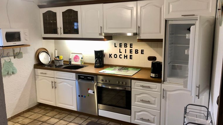 A nice and full furnished kitchen with white cabinets.. On the wall is the phrase "LIVE LOVE COOK".