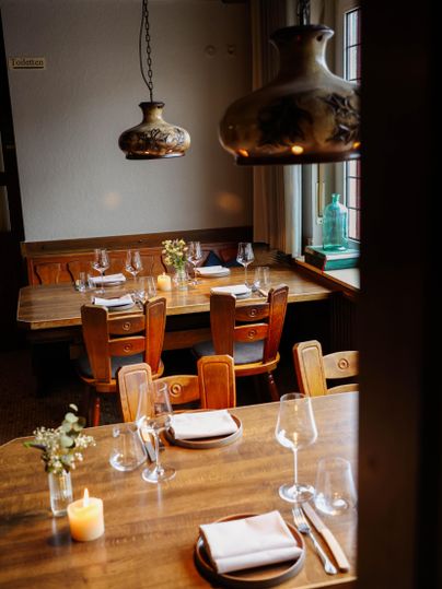 Un restaurant accueillant avec des panneaux en bois et des chaises. Une lumière douce provenant de lampes décoratives crée une atmosphère chaleureuse.