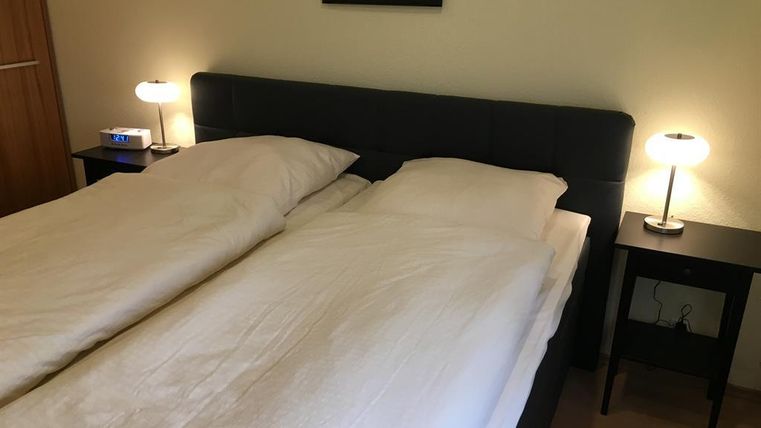 Une chambre moderne avec un lit double et deux tables de nuit. L'éclairage est doux et crée une atmosphère chaleureuse.