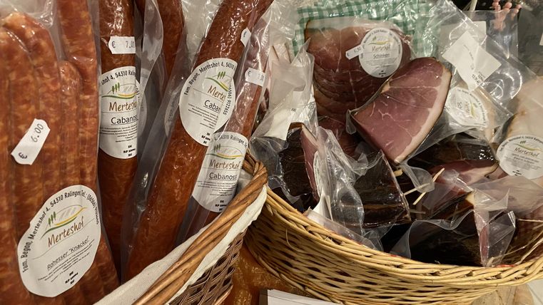 Eine Auswahl an Wurstwaren in einer Korbpräsentation. Die Produkte sind vakuumverpackt und tragen Etiketten mit Preisangaben.