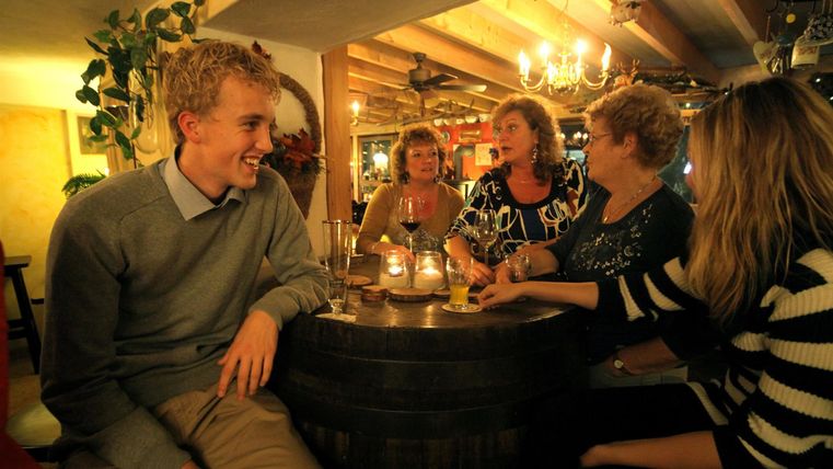 Une table conviviale de cinq personnes dans un restaurant chaleureux. Ils sont assis autour d'une table et discutent joyeusement.