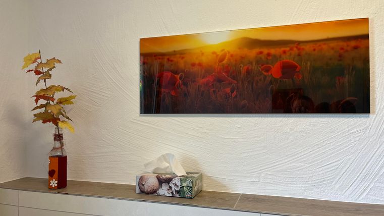 Une chambre moderne avec une grande œuvre murale au-dessus d'un buffet. L'œuvre murale montre des flamants roses devant un paysage ensoleillé et orange.