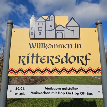 Een welkomstbord voor Ritterdorf met een kleurrijke opmaak. Het bevat informatie over aankomende evenementen op 30.04. en 01.05.