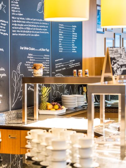 Een moderne café-lounge met een stijlvolle bar. Op de tafel staan stapels bekers en vers fruit.