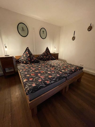 Een gezellig slaapkamer met een groot bed en kleurrijke kussens. De muren zijn versierd met ronde afbeeldingen, en er zijn nachttafels met lampen.