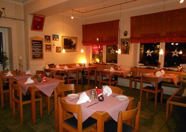 Un restaurant accueillant avec des tables et des chaises en bois. Les tables sont soigneusement dressées et l'éclairage crée une atmosphère chaleureuse.