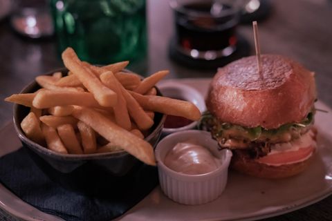 Een lekkere burger met verse sla en een portie friet. Daarbij zijn er ketchup en mayo in kleine bakjes.