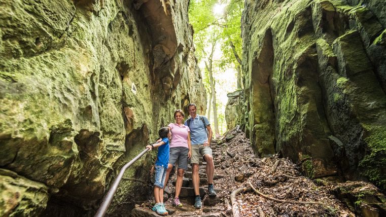 Eine Familie steht auf einem steinigen Pfad in einer grünen Schlucht.