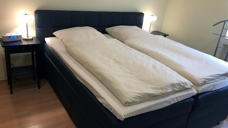 Une chambre moderne avec un lit double spacieux et deux tables de chevet. Les murs sont peints dans une teinte claire, et il y a deux lampes de table.