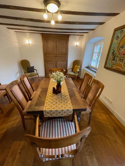 Een uitnodigende eetruimte met een houten tafel en stijlvolle stoelen. Op de tafel ligt een decoratieve tafelkleed met bloemen.