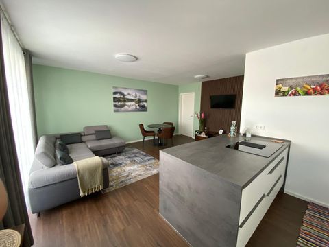 Un salon moderne avec un canapé gris et un coin repas. L'atmosphère lumineuse et accueillante est complétée par de jolis décorations.