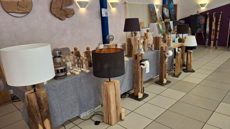 Ein Ausstellungsstand mit Holzlampen und dekorativen Holzobjekten. Der Raum hat eine helle, einladende Atmosphäre.