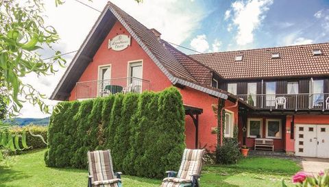 A red house with a green garden and cozy lounge chairs. The sky is clear and there is a peaceful atmosphere.