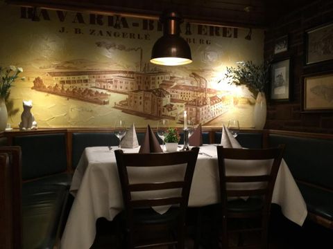 Ein gemütliches Restaurant mit einer elegant gedeckten Tischdeko. An der Wand hängt ein historisches Bild einer Fabrik.