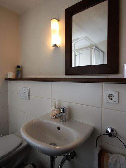 Ein modernes Badezimmer mit einem Waschbecken und einem Spiegel. Die Wände sind hell und gut beleuchtet.