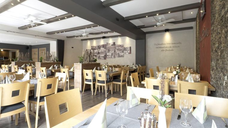 Een modern restaurant met lichte houten meubels en stijlvolle decoratie. Tafels zijn liefdevol gedekt en creëren een uitnodigende sfeer.