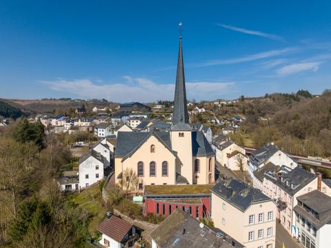 Une petite ville avec de nombreux bâtiments et une église marquante au premier plan. Le clocher s'élève haut dans le ciel bleu clair.