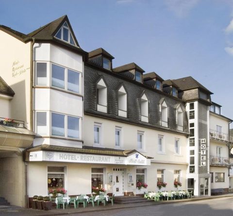 Ein charmantes Hotel mit Restaurant, das eine einladende Fassade und große Fenster hat. Es gibt Sitzmöglichkeiten im Freien und eine ruhige Umgebung.