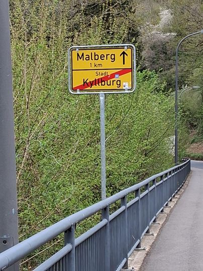 Un panneau indique la direction de Malberg, à 1 km. La ville de Kyllburg est rayée.