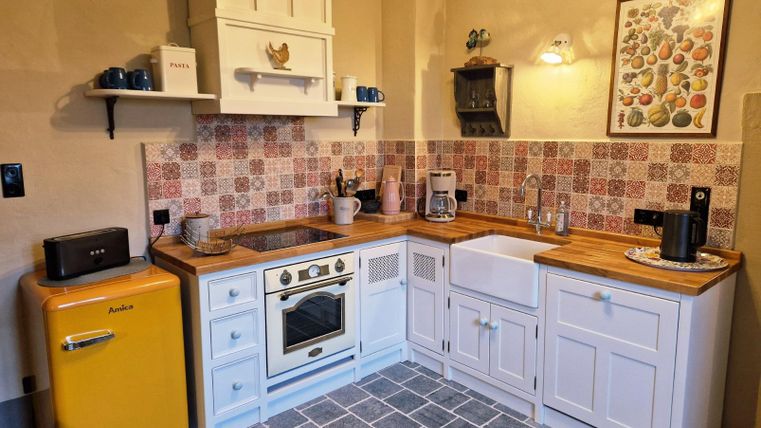 Een moderne keuken met een gele koelkast en een witte spoelbak. De muren zijn versierd met kleurrijke tegels, en er zijn houten oppervlakken evenals een gezellige sfeer.