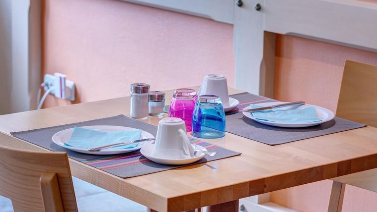 Une table dressée avec des verres et de la vaisselle colorés. L'atmosphère est accueillante et amicale.