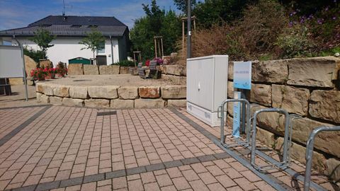 Een geplaveide oppervlakte met een stenen trappenbank en fietsenrekken. Op de achtergrond is een gebouw en enkele planten te zien.