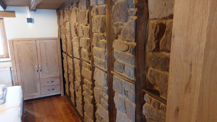 Een gezellige kamer met een stenen gevel en houten meubels. De warme sfeer nodigt uit om te ontspannen.