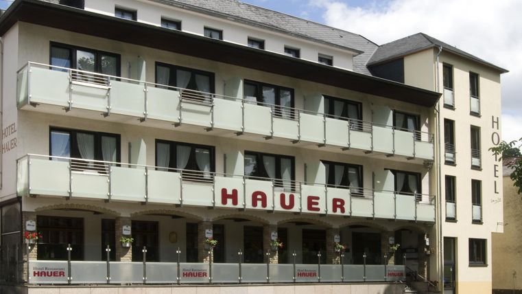 Un hôtel moderne avec des balcons et le nom « Hauer » sur la façade. L'architecture est élégante et accueillante.