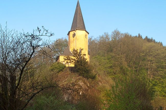 Wallfahrtskirche auf einem Hügel umgeben von Bäumen.